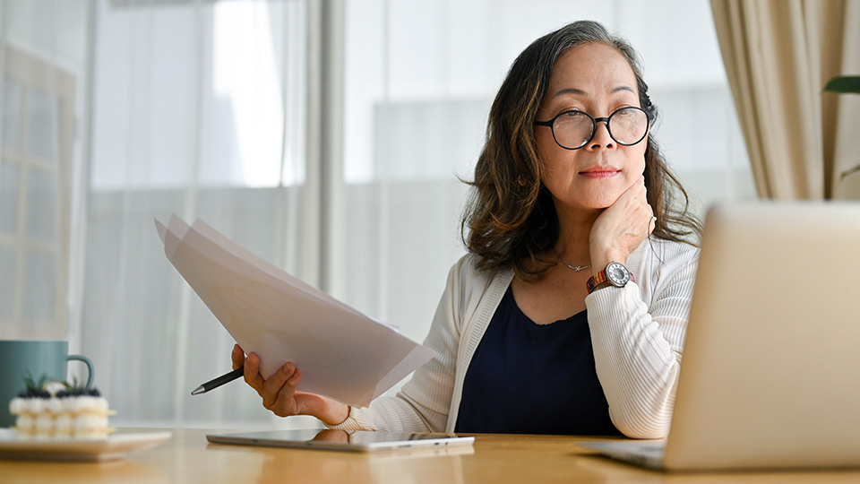 Educator reviewing papers and providing feedback using AI at a desk