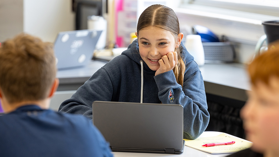 Student using AI on a laptop in a classroom with other students
