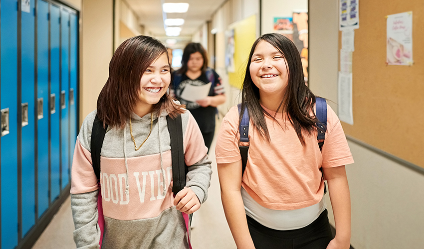 Two students walking through a school hallway together